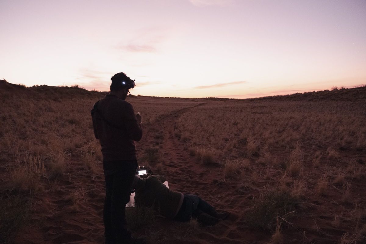 Pilot in FPV goggles and headlamp preparing a heavy lift drone for a night flight in the Namib